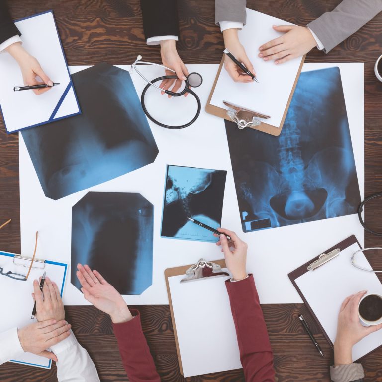 Group of doctors sitting around a wooden table at a medical conference