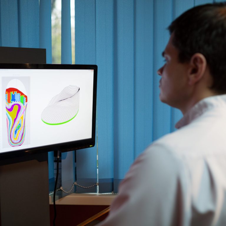 Orthopaedist at work with computer. He modeling orthopedic shoe using foot scan